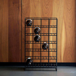 Zwart metalen wijnrek met vijf flessen voor een houten wand