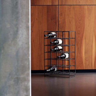 Zwart metalen wijnrek met vijf flessen voor een houten wand en betonnen wand