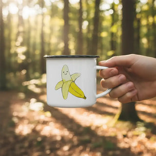 Ligarti emaille mok Banaan (300 ml) in een hand buiten, met de gele banaanillustratie vrij zichtbaar.
