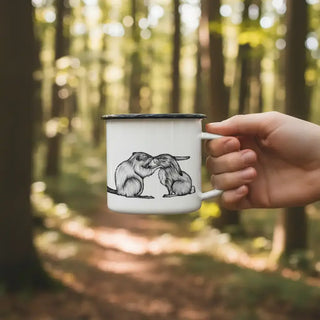 Ligarti emaille mok Bever & Konijn (300 ml) in een hand buiten, met bever en konijn zichtbaar tegen een zachte bosachtergrond.