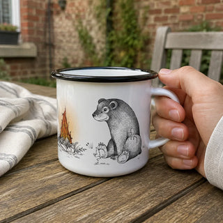 Ligarti emaille mok bosvrienden bij het vuur – 300 ml van dichtbij in gebruik, met de illustratie en dunne zwarte emaille rand zichtbaar.
