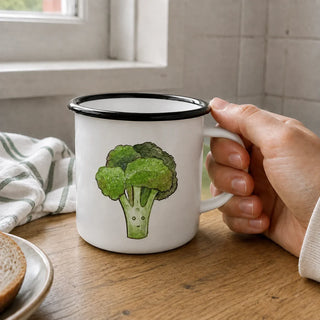 Ligarti emaille mok broccoli – 300 ml van dichtbij in gebruik, met de illustratie en dunne zwarte emaille rand zichtbaar.