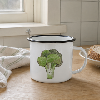 Ligarti emaille mok broccoli – 300 ml in een natuurlijke alledaagse omgeving, met de originele illustratie zichtbaar.