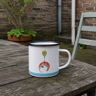 Ligarti emaille mok Garnaal op Pad 300 ml op een houten tafel in een bakstenen binnentuin.