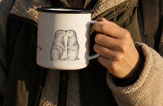 Ligarti emaille mok Hartzeer op de Prairie (300 ml) in de hand, in een uitsnede van de gebruiksfoto, met twee prairiehonden op de voorkant.