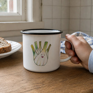 Ligarti emaille mok Venkel 300 ml bij een gewone keukentafel met katoenen theedoek en zacht strijklicht langs het emaille.