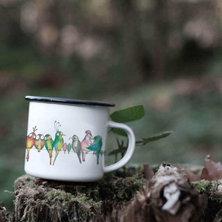Bird parade-emaille mok met vogelillustratie op een bemoste boomstronk in het bos