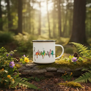 Witte mok met kleurrijke vogelillustraties en zwarte rand op een bemoste boomstam in het bos