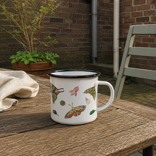 Ligarti emaille mok Bonte Motten 300 ml op een gewone tuintafel in zacht avondlicht, met duidelijke kleurrijke opdruk.