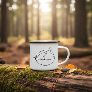 Witte emaille mok met slapende-vosillustratie op een met mos begroeide boomstam in het bos