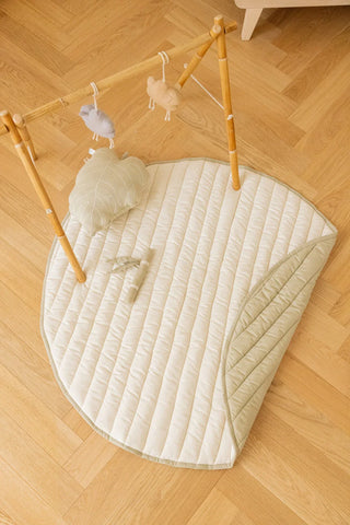 Naturel zijde van de Bamboo Leaf-speelmat onder een houten babygym, met los bamboespeeltje.