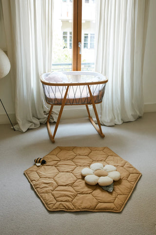Honey-speelmat bij een wieg in een lichte kamer.