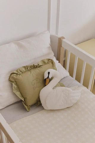 Ivoorkleurige Vichy-deken in een kinderbed met zwaankussen.