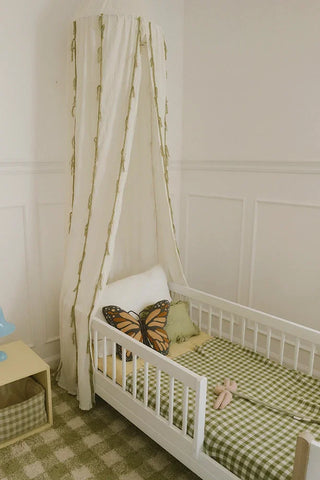Naturel deken met groene ruiten over de rand van een kinderbed.