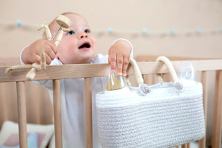 Mand hangt aan de rand van een babybed.