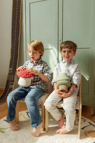 Kind met kleine groene boommand naast een kind met paddenstoelmand.