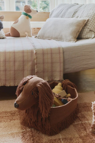 Poppy-hondenmand met speelgoed naast een bed.