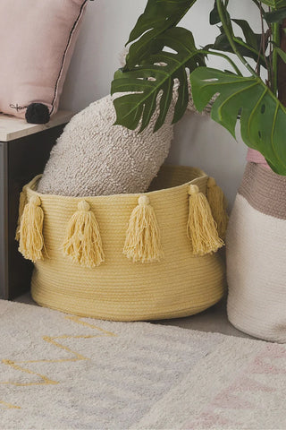 New Tassels Honey mand met opgerold textiel naast een plant
