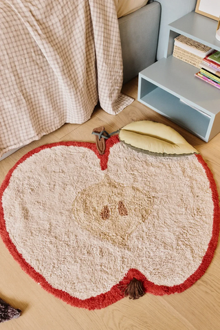 Appelvloerkleed naast een bed en een nachtkastje.
