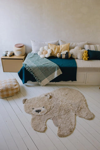 Honingkleurig Bear-vloerkleed op een lichte vloer voor een bed.