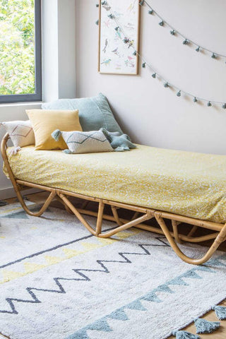 Azteca Vintage Blue vloerkleed naast een rotan bed