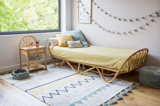 Vloerkleed met blauwgroene driehoeken voor een bank.