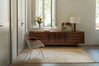 Goudkleurig Bloom-vloerkleed met hoekkwasten voor een dressoir.