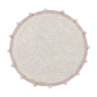 Rond naturel vloerkleed met roze rand en pompons.