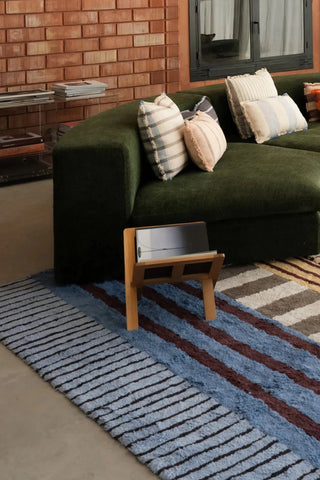 Blauw Color On-vloerkleed voor een groene bank.