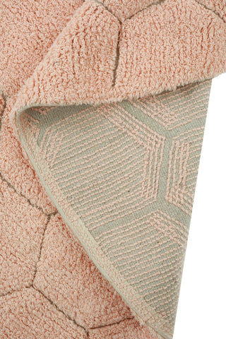 Omgeslagen hoek toont de achterkant van het roze Comb-vloerkleed.