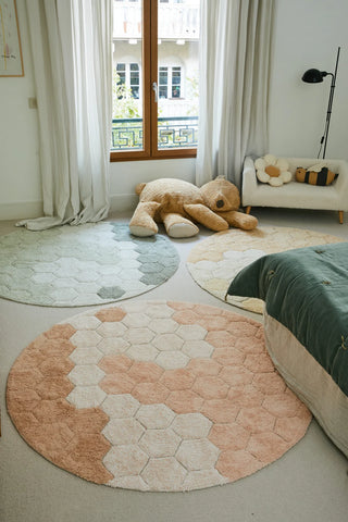 Roze Comb-vloerkleed bij een bed in een lichte kamer.