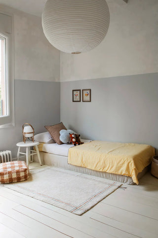 Naturel Cuisine-vloerkleed met blauwe en bruine lijnen naast een kinderbed.