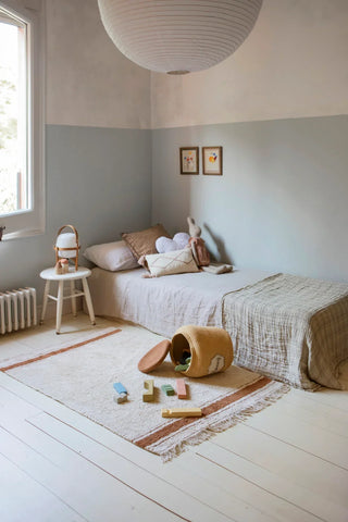 Naturel Gastro-vloerkleed met toffeekleurige strepen naast een kinderbed.