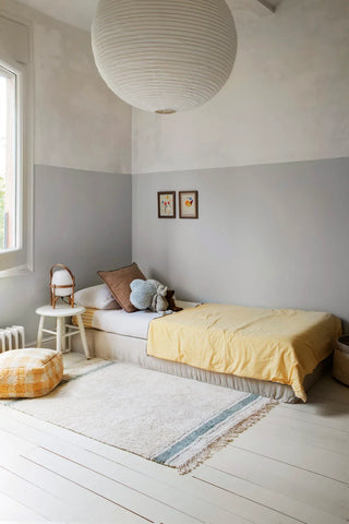 Naturel Gastro-vloerkleed met blauwe strepen naast een kinderbed.
