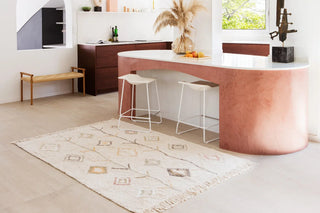 Naturel Kaarol-vloerkleed met gekleurde ruitmotieven en franjes in een lichte keuken.