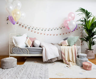 Licht vloerkleed met gekleurde motieven bij een bed.