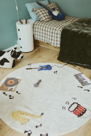 Rond Music-speelkleed op de vloer naast een bed.