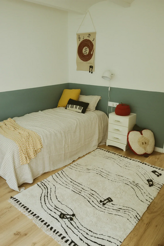 Lorena Canals Notes vloerkleed met muzieknoten naast een bed