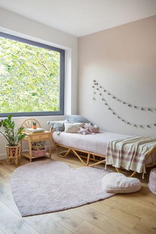 Hartvloerkleed met hartkussen bij een bed.