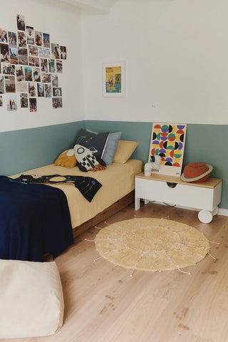 Honingkleurig zonvloerkleed naast een kinderbed.