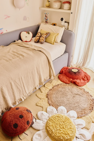 Zonnebloemvloerkleed naast een bed in een kinderkamer.