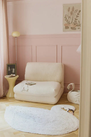 Ivoren zwaanvloerkleed op de vloer in een roze kinderkamer.