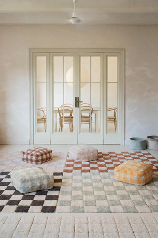 Roze en naturel Kitchen Tiles-vloerkleed links achter in een groep vloerkleden en poefs.
