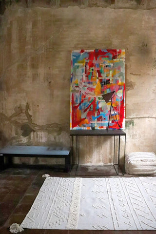 Naturel Tribu-vloerkleed met verhoogde geometrische motieven bij een kunstwerk.