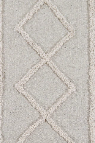 Detail van naturel Tribu-vloerkleed met verhoogde ruiten en vlak geweven ondergrond.