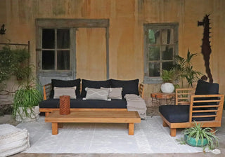 Naturel Tribu-vloerkleed met verhoogde geometrische motieven bij houten loungemeubelen.
