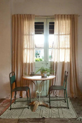 Olijfgroen Tribu-vloerkleed met verhoogde geometrische motieven onder een ronde tafel.