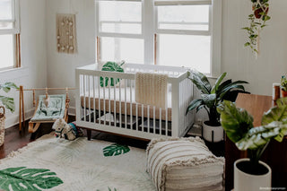 Vloerkleed met tropische bladeren bij een babybed.