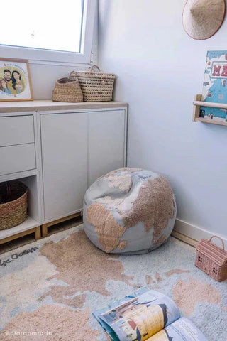 Wereldkaartvloerkleed naast een wereldbolpoef.