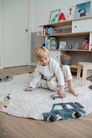 Kind speelt op het ronde Wheels-vloerkleed.